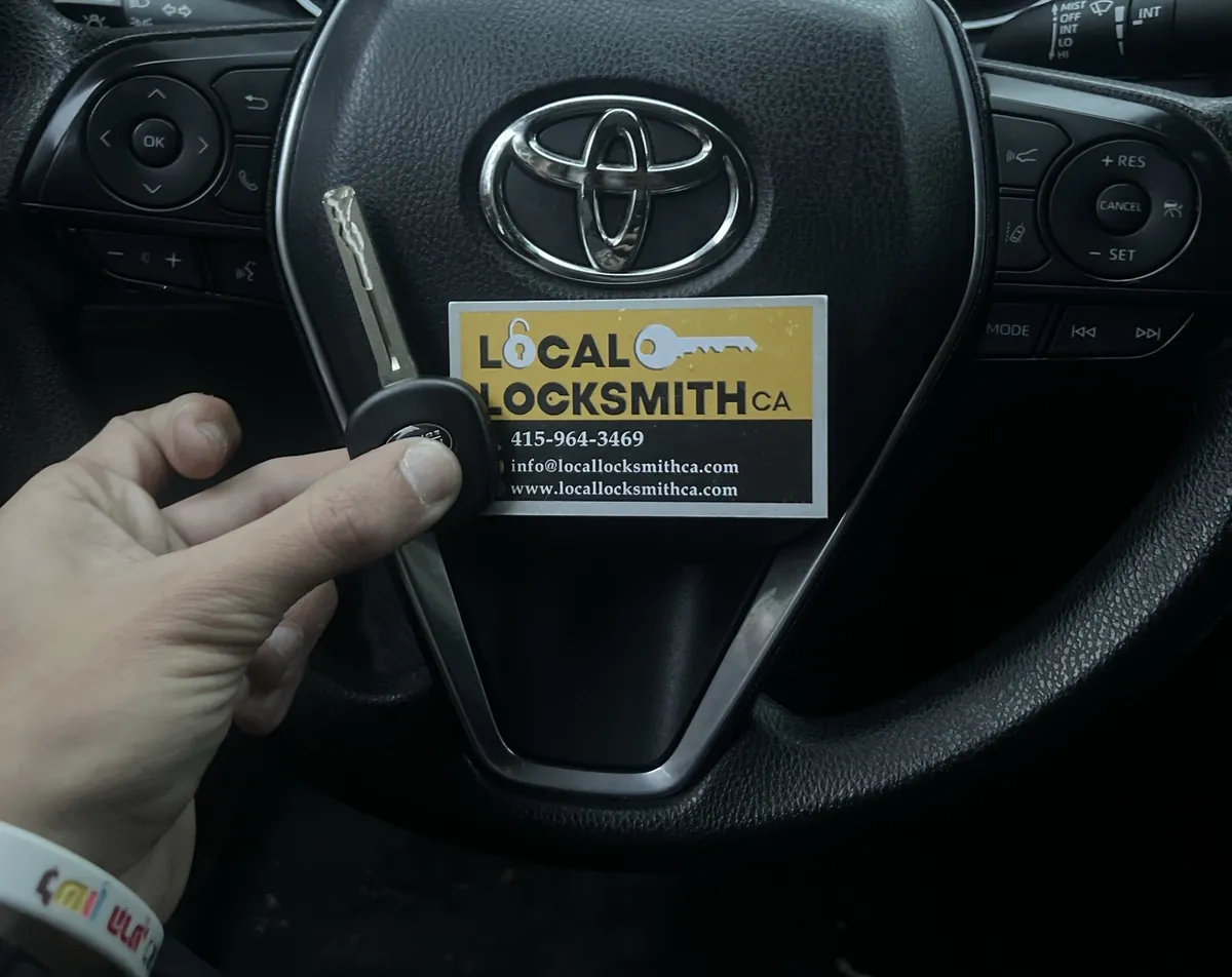 New Toyota key held up in front of the steering wheel